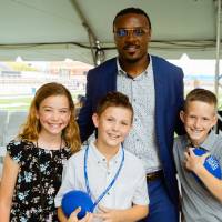 Three children posing with a guest at the Jamie Hosford Football Center dedication.